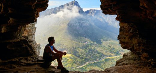 photo of man sitting on a cave