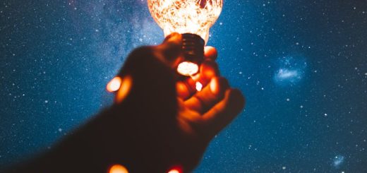 person holding light bulb with string lights inside