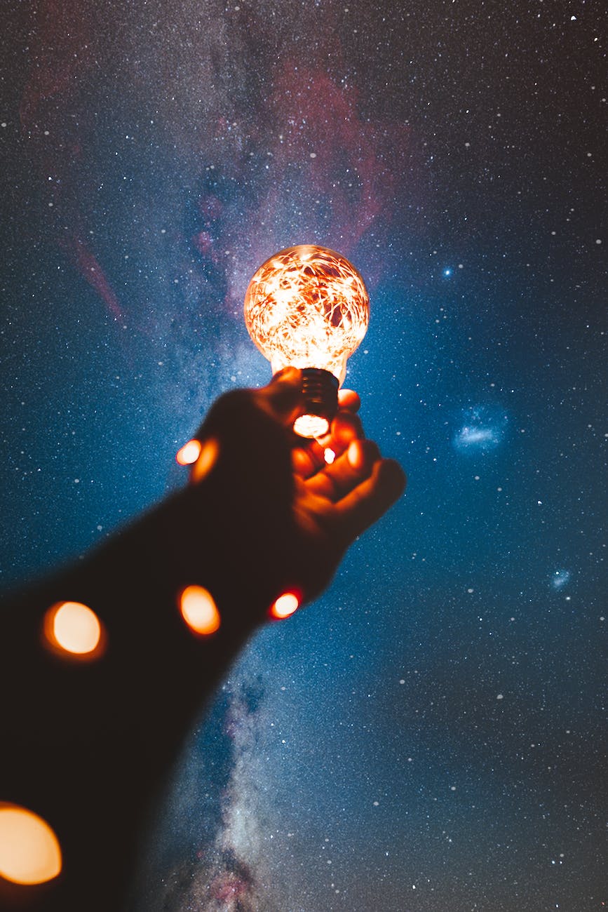 person holding light bulb with string lights inside