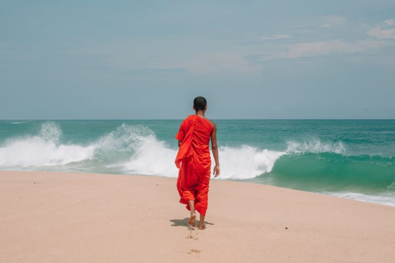 unrecognizable young ethnic man walking on seashore