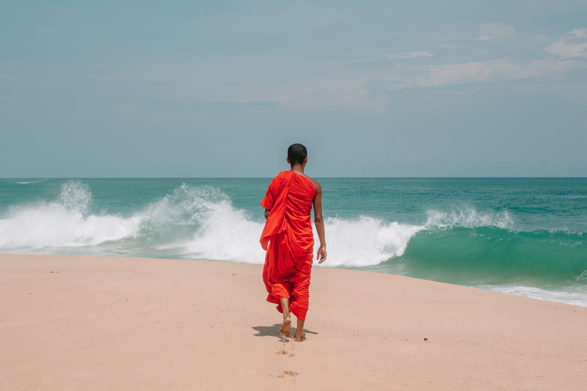 unrecognizable young ethnic man walking on seashore