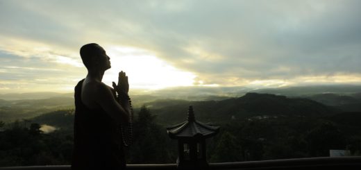 monk holding prayer beads across mountain