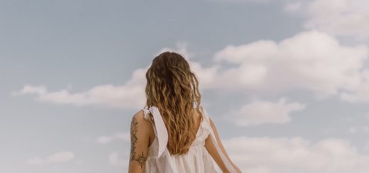 unrecognizable tattooed woman admiring ocean under cloudy sky