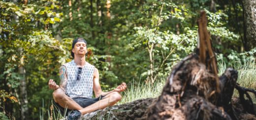 man meditating on a tree log