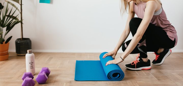 crop fit sportswoman unfolding fitness mat on floor