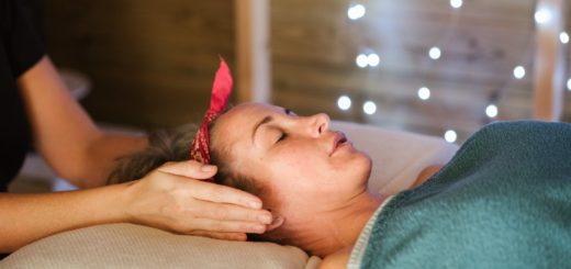 crop masseuse with hands near ears of woman