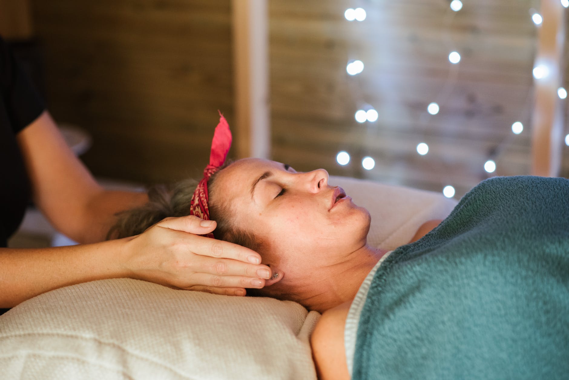 crop masseuse with hands near ears of woman