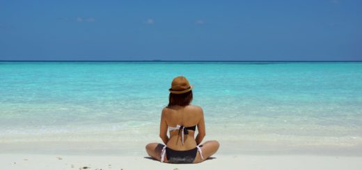 woman wearing black and white brassiere sitting on white sand