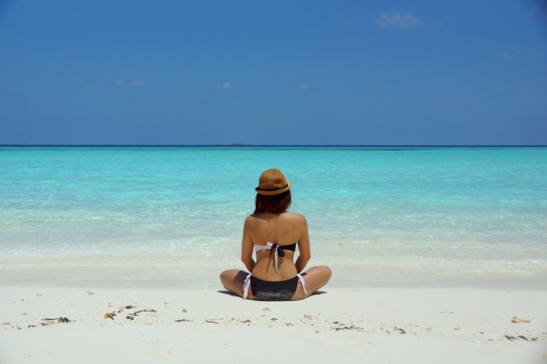 woman wearing black and white brassiere sitting on white sand