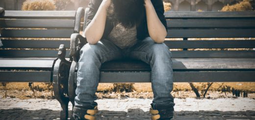 man in black shirt and gray denim pants sitting on gray padded bench