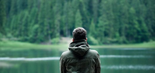 photo of man wearing hooded jacket in front of body of water