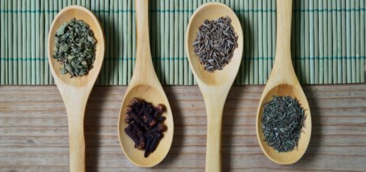 brown wooden spoon with herbs on top of green bamboo mat and brown wooden surface