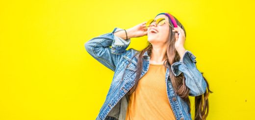 smiling woman looking upright standing against yellow wall