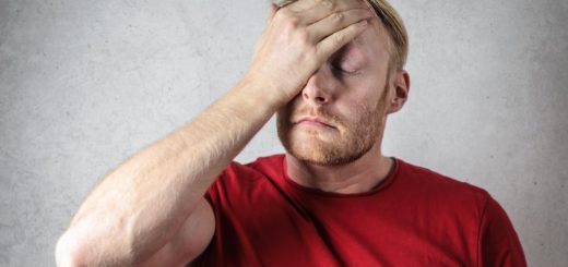 a man in red shirt covering his face