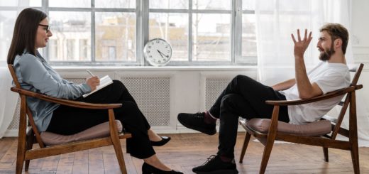 person in black pants and black shoes sitting on brown wooden chair