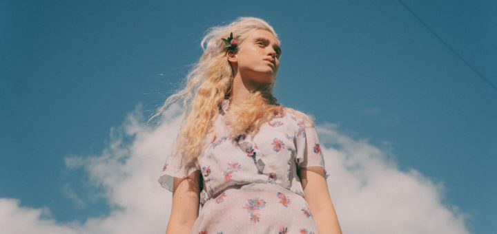 gentle woman with flower in hair under blue sky