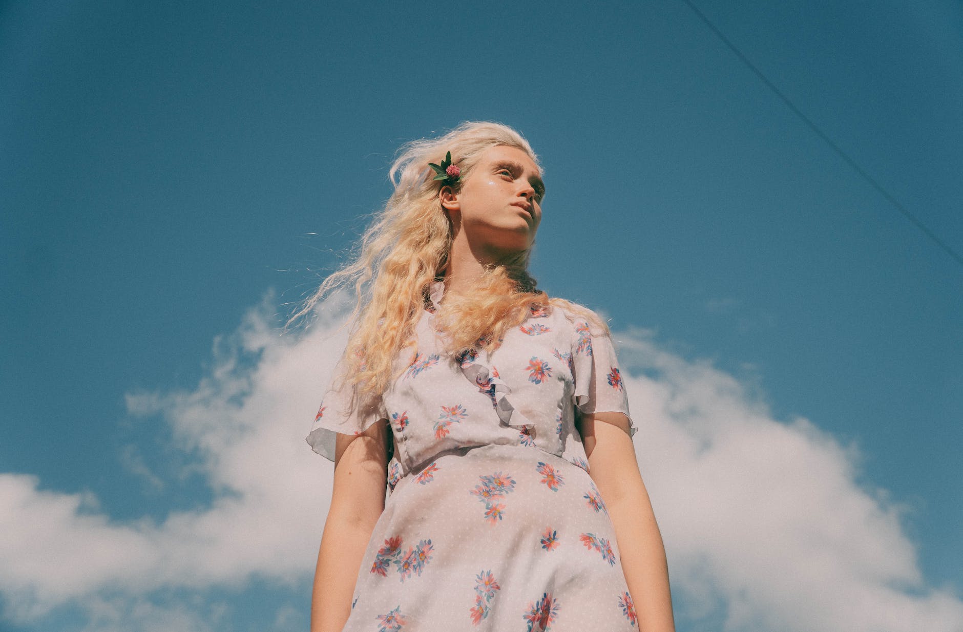 gentle woman with flower in hair under blue sky