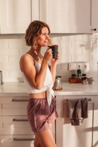 happy woman drinking coffee in kitchen