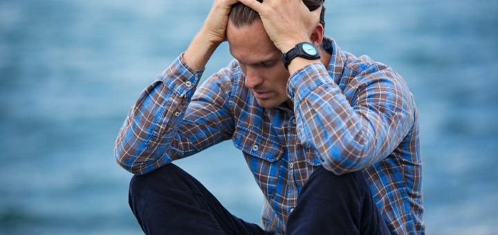 man in blue and brown plaid dress shirt touching his hair