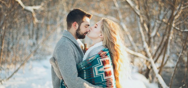 man and woman hugging each other about to kiss during snow season