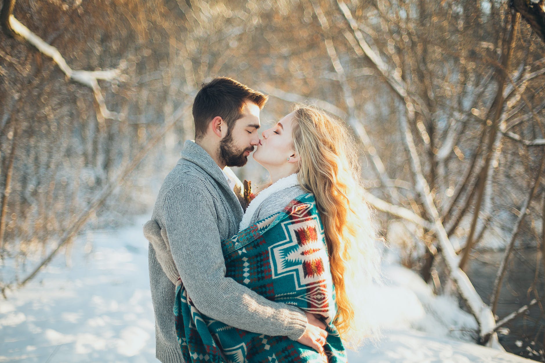 man and woman hugging each other about to kiss during snow season