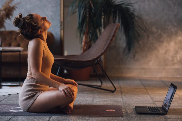 photo of a woman stretching her neck near her laptop