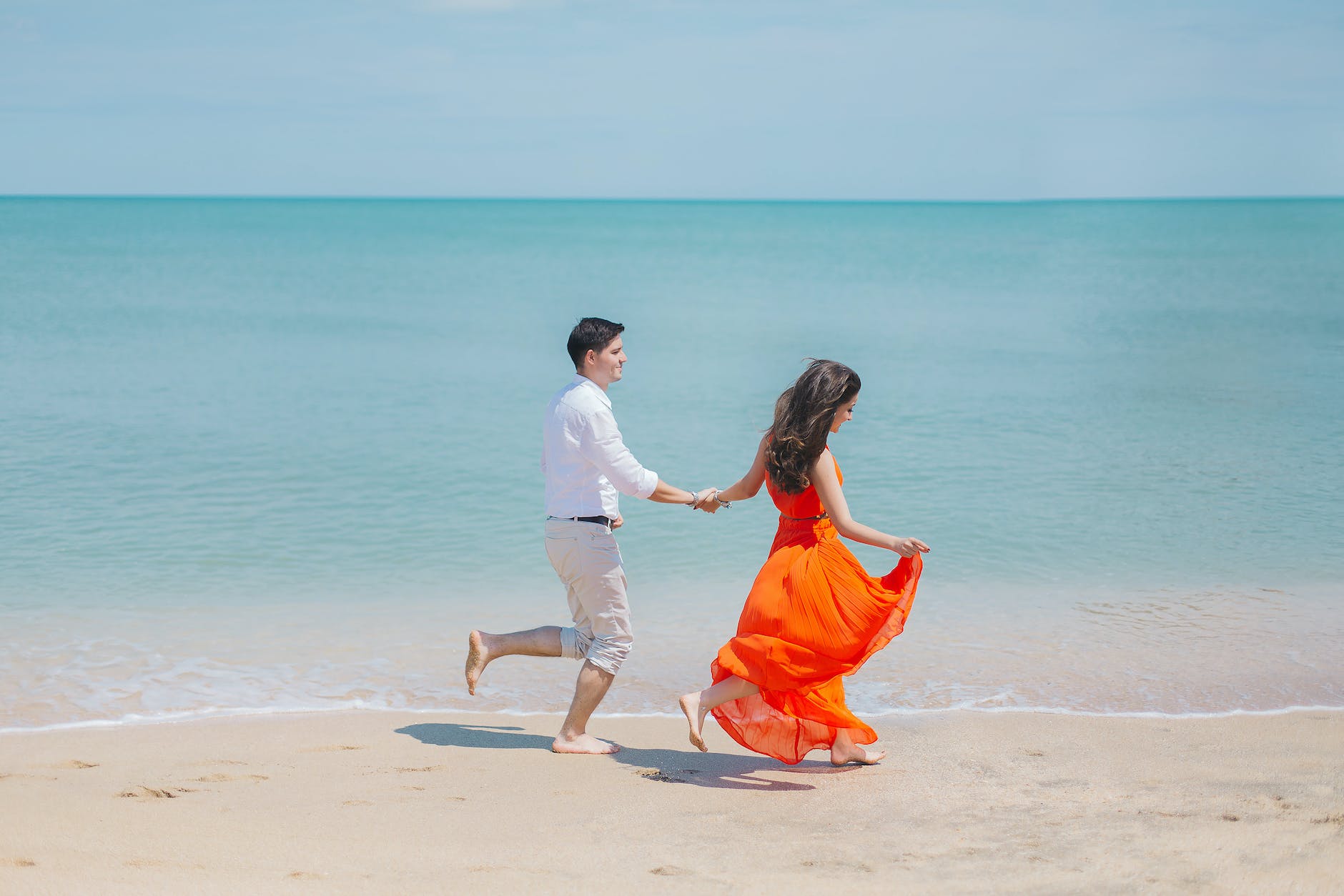 man and woman walks beside green sea