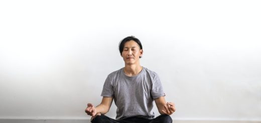 photo of man in gray t shirt and black jeans on sitting on wooden floor meditating