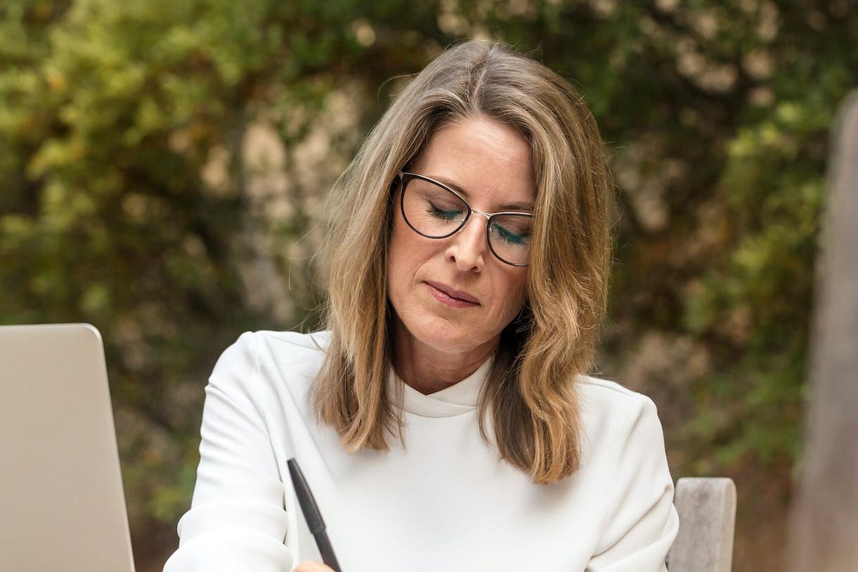 woman sitting on gray chair while writing on table