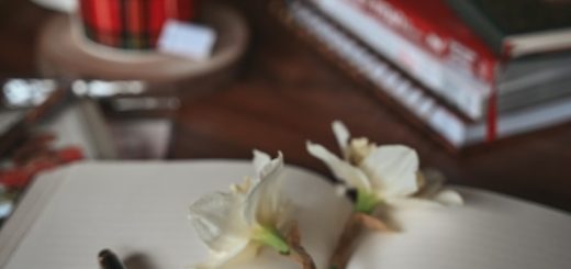 a notebook with a pen and flowers on a table