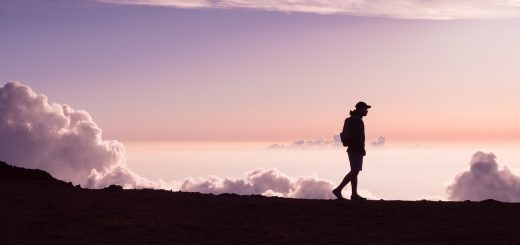 silhouette of person walking under white clouds