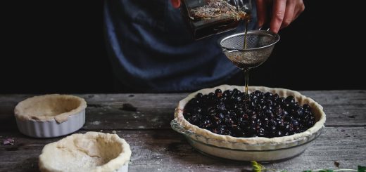 person pouring liquid on blackberry pie