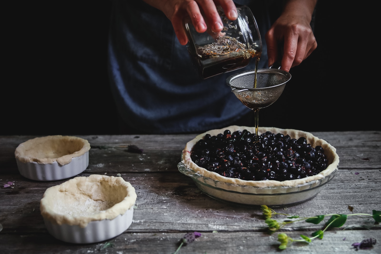 person pouring liquid on blackberry pie