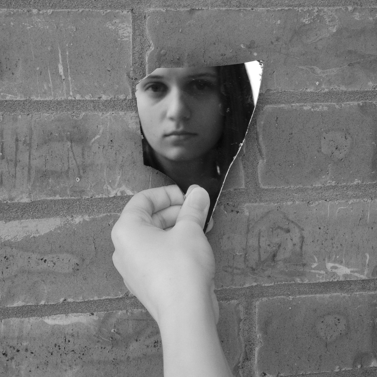 a woman leaning against a brick wall